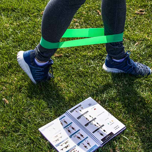 Woman exercising with green resistance band, using the Fitbride workout book
