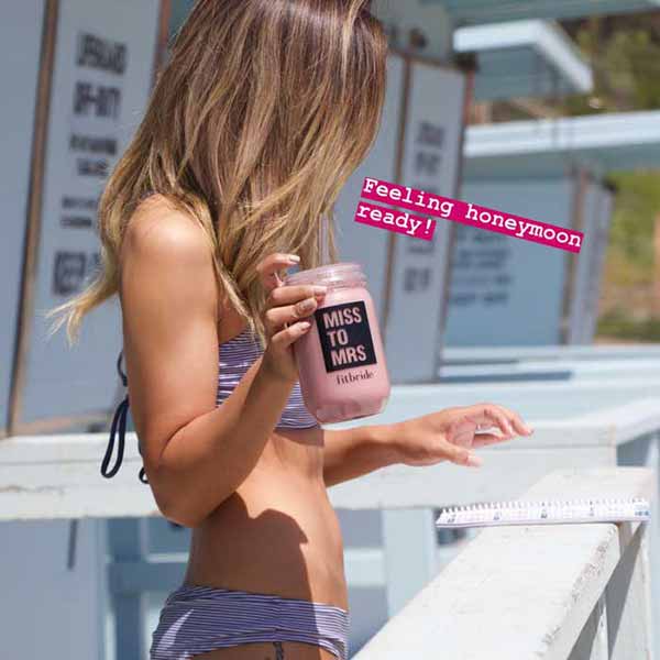 Woman in bikinin drinking a Fitbride shake on the beach